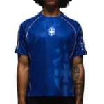 Person wearing a royal blue athletic jersey with white piping and a crest on the chest.