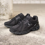 Pair of black athletic sneakers with chunky soles resting on a concrete surface beside a pillar.