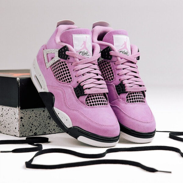 Pair of pink purple high-top sneakers with black accents on a speckled box and loose black laces nearby