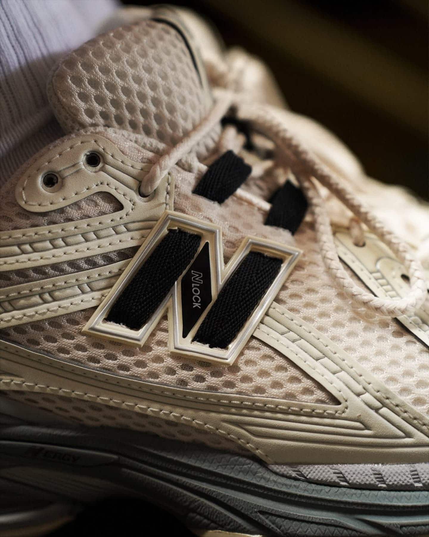 487418592_629338723251334_2971081268871151186_n | UAE SPORT STORE Close-up of a beige mesh sneaker showing laces, eyelets, and the white New Balance 'N' logo badge on the side.