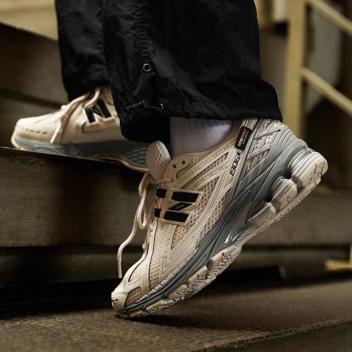 487423837_503926906124796_9218447376320132549_n | UAE SPORT STORE White and gray running shoes with a chunky sole stepping onto a metal stair; person wearing black pants and white socks.