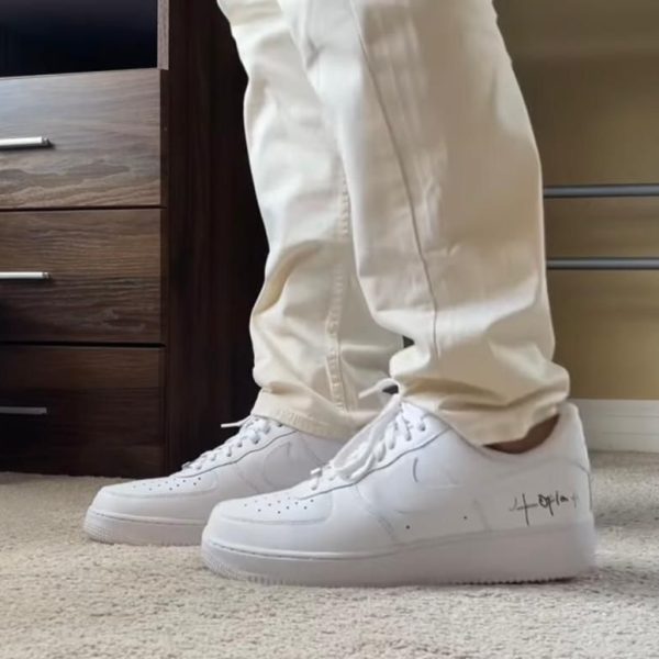 Person wearing white sneakers and beige pants standing on a carpet in a bedroom next to a wooden dresser.