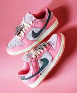 Pair of pink and gray Nike sneakers with a glittery dark teal swoosh on a pink background