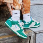 Teal and white Nike sneakers with white socks balancing on a concrete step.