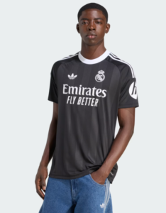 Young man wearing a black Real Madrid football jersey with Emirates Fly Better logo, standing with one hand in his pocket.