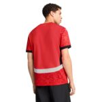 Back view of a man in a red athletic jersey with patterned sleeves and a white reflective band at the hem.
