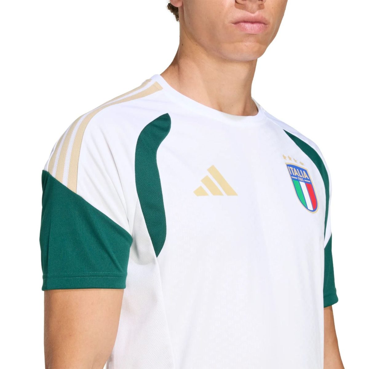 Close-up of a white Italy football jersey with green sleeves and gold Adidas stripes, showing the crest on the chest.