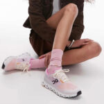 Person seated with legs crossed, wearing pastel pink running shoes and matching pink socks.