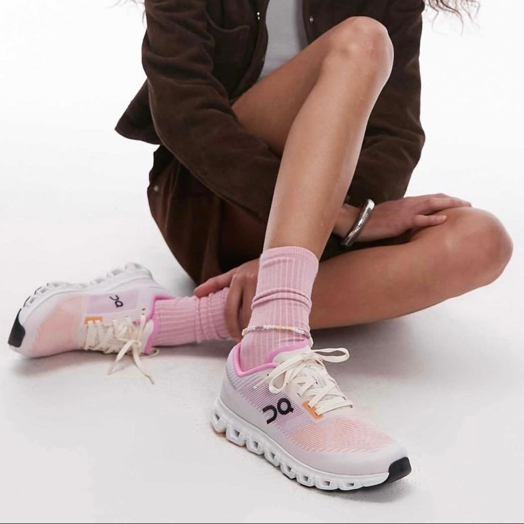 4af635b1-237f-46ec-a07b-1d5a7866ea4b Person seated with legs crossed, wearing pastel pink running shoes and matching pink socks.