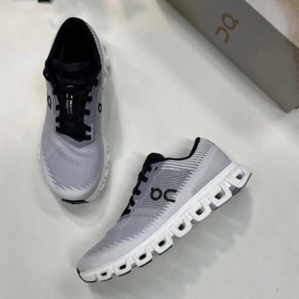 Pair of gray On running shoes with black laces on a white surface, showing the side and top view with a box in the background.