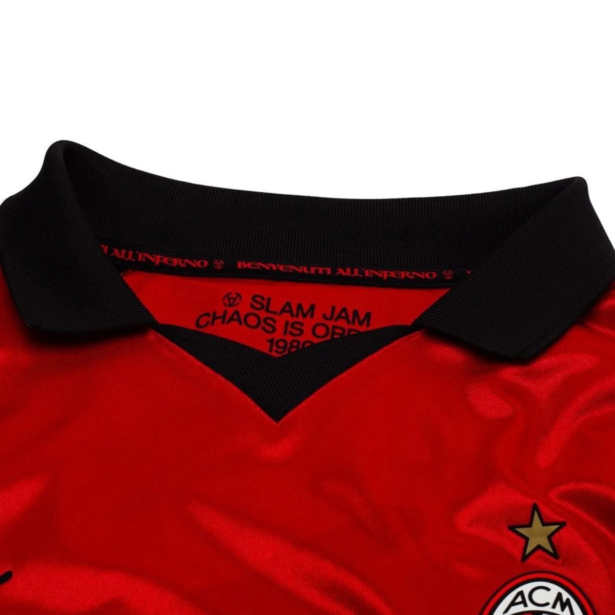 Close-up of a red shirt with a black ribbed collar, showing graphic text and logos along the neckline (includes 'SLAM JAM' and 'ACM' with stars).
