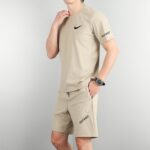 4bfdfa40 | UAE SPORT STORE Person in beige athletic shirt and shorts, with a black Nike swoosh on the chest and 'JUST DO IT' on the leg area.