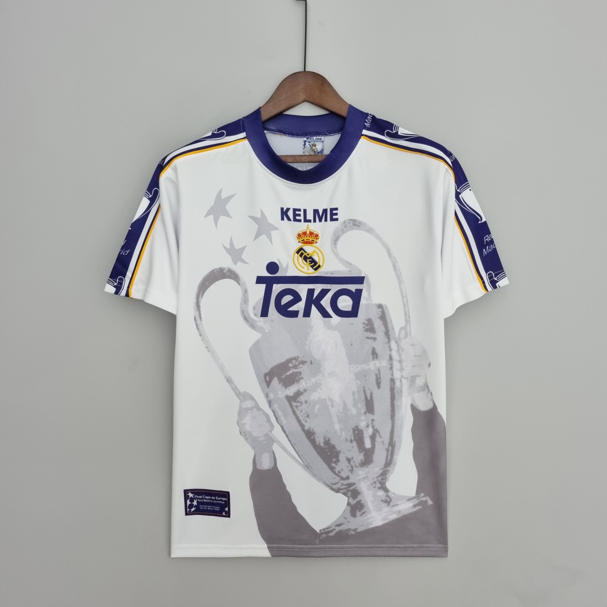 4c6323f9_592bd298-b142-4b35-a279-f81d14e245bd | UAE SPORT STORE White Real Madrid sports jersey on a wooden hanger, centered on a gray background, featuring TEKA sponsor and crest.