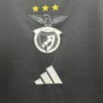 Silver eagle emblem with outstretched wings above a circular badge, three gold stars aligned on dark fabric behind it.