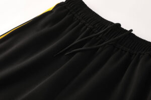 Close-up of black athletic shorts with an elastic waistband and black drawstrings, small yellow accent stripe visible on the side.