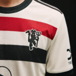 Close-up of a striped sports jersey with red, white, and black bands and a black devil mascot emblem on the chest.