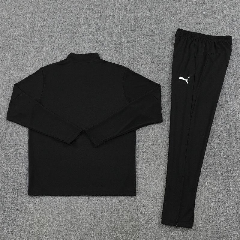 4ddad66a-f84b-4fbb-90be-6182f4ce850d | UAE SPORT STORE Black athletic tracksuit top and matching pants laid out on a gray carpet; white Puma logo on the pants.