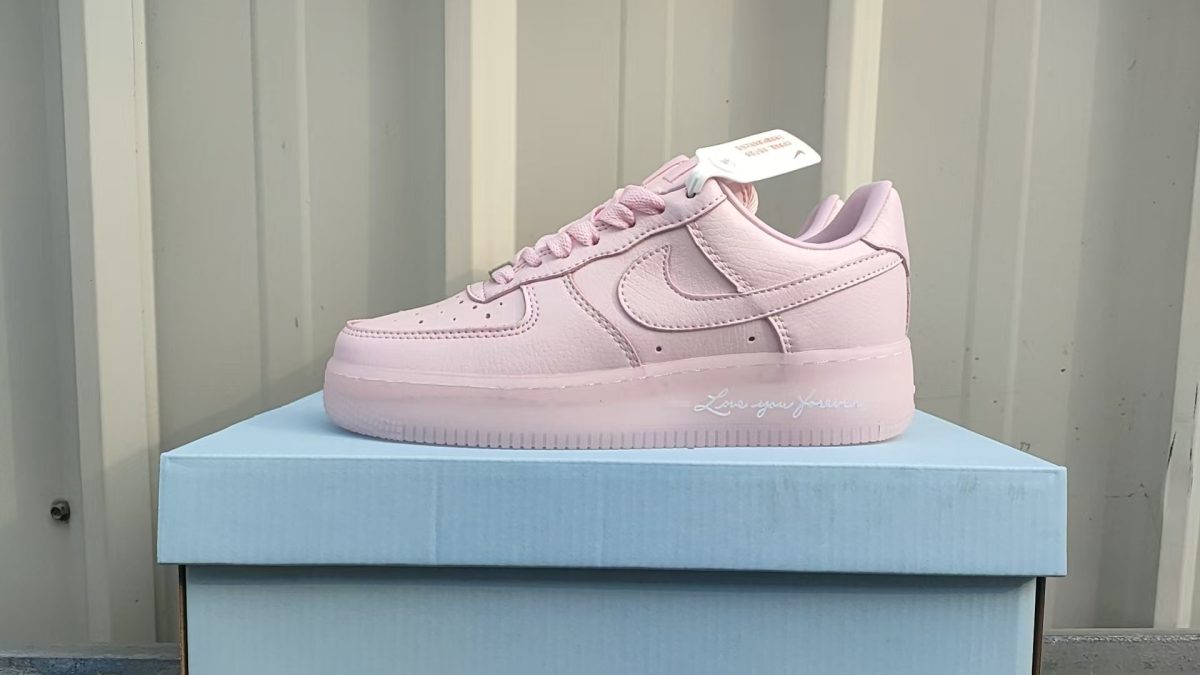 Pink Nike Air Force 1 sneaker in pastel pink on a light blue box, side view with 'Love you forever' on the midsole.