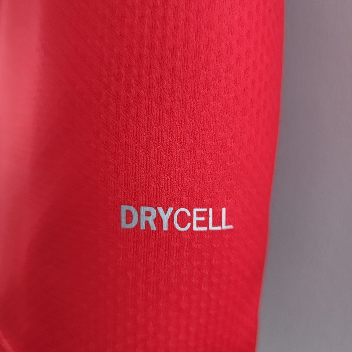 Close-up of red fabric with white text reading 'DRYCELL' near the lower edge, showing a soft, textured surface.