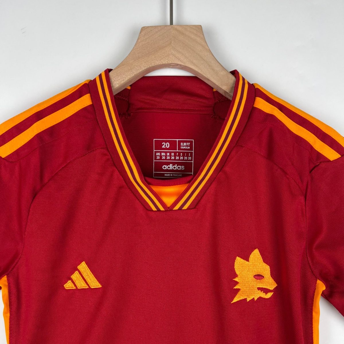 Red Adidas sports jacket on a wooden hanger with orange and yellow shoulder stripes.