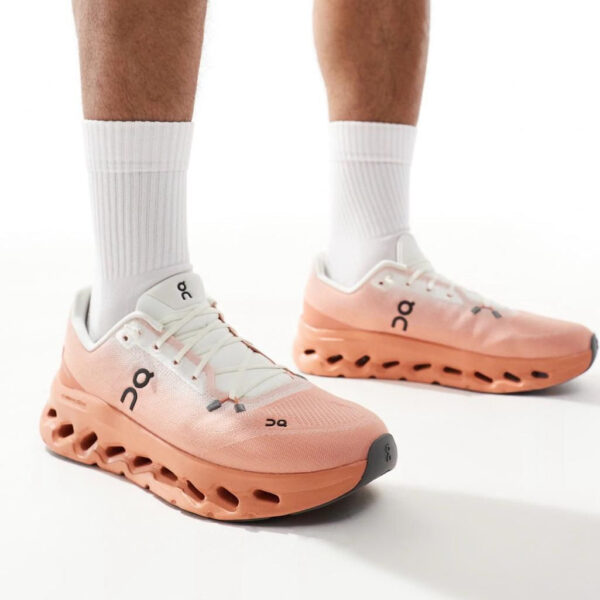 Peach new running shoes with thick, hollowed-out sole and white laces, worn with white crew socks (brand logo visible).