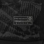 4f738d25_20c2_4bfb_beb6_5b1564f70680 | UAE SPORT STORE Close-up of a dark patterned fabric label that reads ENGINEERED with a small emblem to the right.
