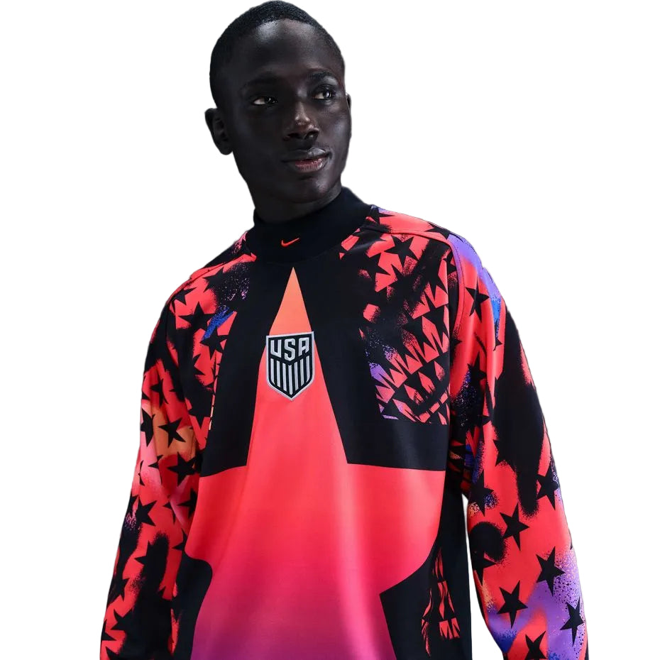 4fbbe68a-e0bc-49d4-ada2-52b61a0ebaaa Young man wearing a vibrant pink and black USA team jersey with star patterns and a crest on the chest.