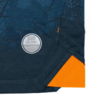 50 | UAE SPORT STORE Close-up of dark blue fabric with a circular silver logo patch and a bright orange interior corner.