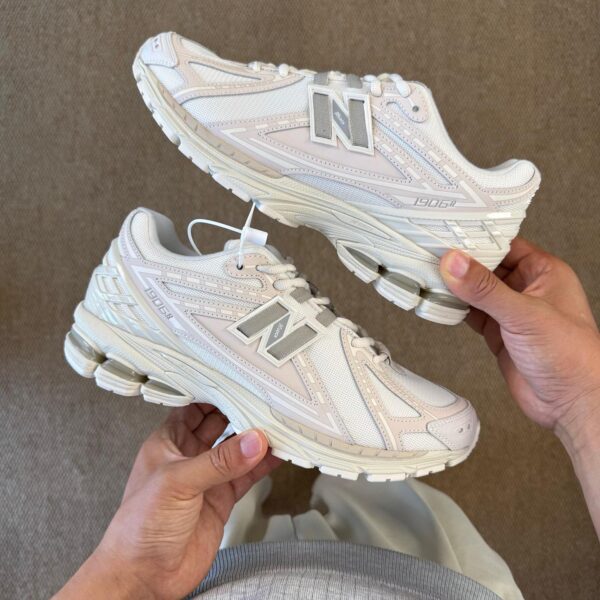 White New Balance 1906R sneakers held apart to show details.