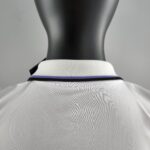 Back view of a black mannequin wearing a white polo shirt with a purple/blue striped collar viewed from behind.