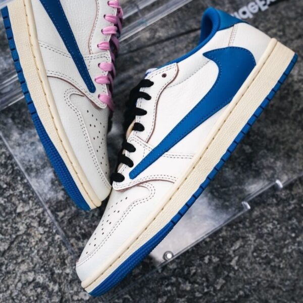 Pair of white sneakers with blue accents and contrasting lace colors (pink on left shoe, black on right) resting on a dark surface.