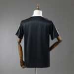 Back view of a dark, short-sleeve striped shirt on a mannequin, showing subtle vertical stripes and a white collar visible at the neck.
