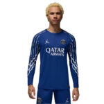 Young man wearing a blue Paris Saint-Germain football jersey with Qatar Airways sponsor, team crest on the chest, and white sleeve stripes.