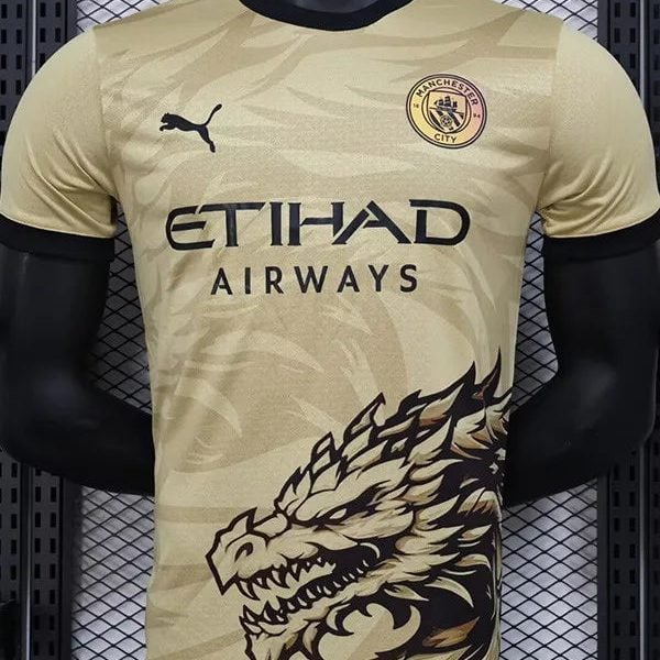 Beige Manchester City football jersey on a mannequin, showing club crest, Puma logo, Etihad Airways sponsor, and a large dragon graphic on the lower front.