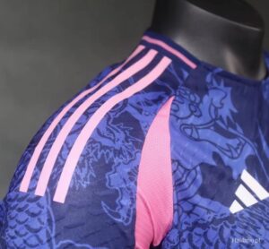 Close-up of a blue patterned sports jersey with pink panels and three light pink stripes on the shoulder, displayed on a mannequin (Adidas style).