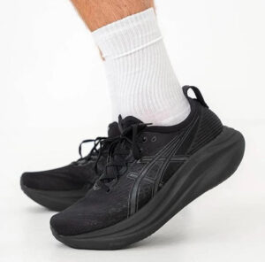 Black running shoes with a cushioned sole worn with white crew socks, mid-step pose.