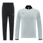 Nike black jogger pants paired with a light gray quarter-zip training top featuring a black collar and Nike swoosh logo on each piece.