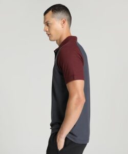Side profile of a man wearing a color-block polo shirt with maroon sleeves and dark gray torso, standing against a light gray background.