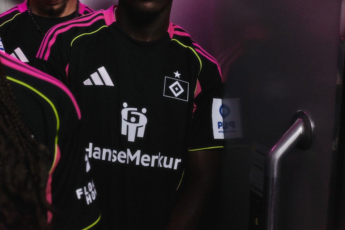 Close-up of a person in a black sports jersey with pink and neon-green trim and logos on chest area