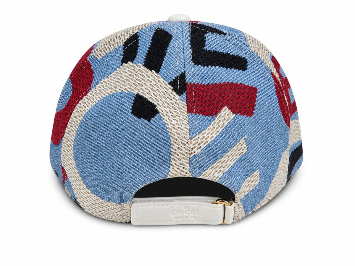 Back view of a multicolored woven cap with beige, blue, red and black geometric patterns, white adjustable strap with Gucci logo.