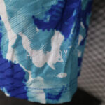 Close-up of blue and teal patterned fabric with white lettering.