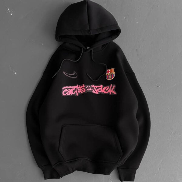 Black hoodie with a pink graffiti-style 'cactus jack' graphic across the chest, small Nike swoosh above, and FC Barcelona crest on the upper left.