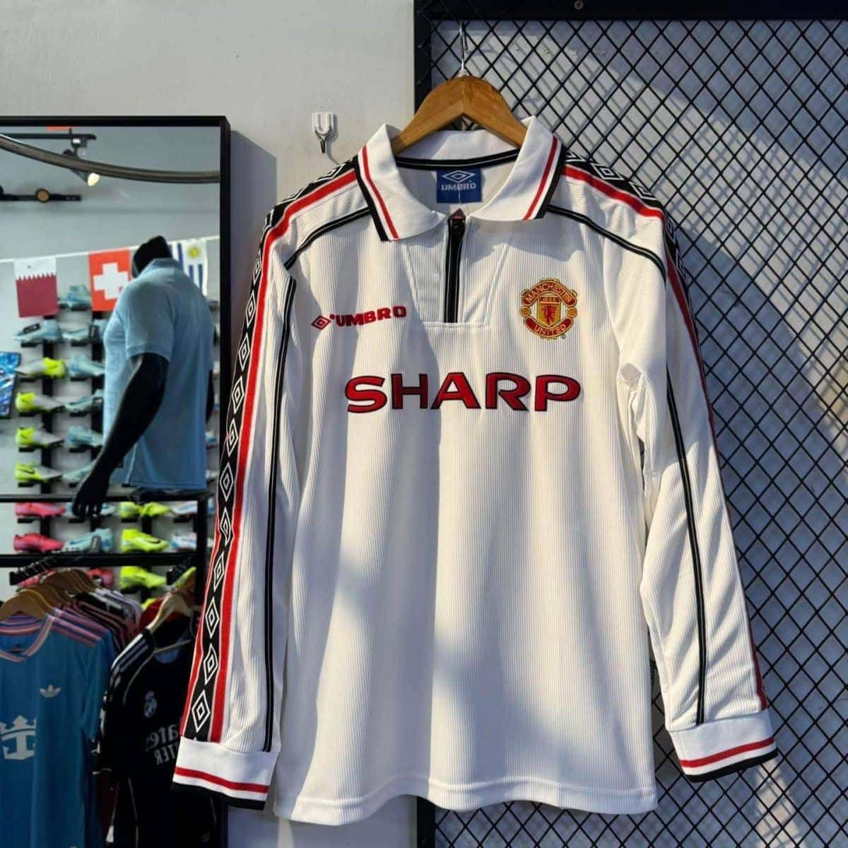 Manchester United white long-sleeve jersey with red sponsor SHARP and club crest on display.