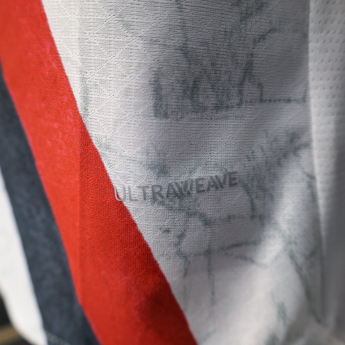 Close-up of gray denim fabric with a bold red stripe.