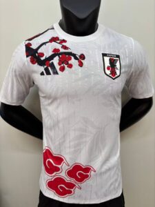 White Japan national football team jersey featuring a cherry blossom branch, Adidas logo, and JFA crest on the chest.
