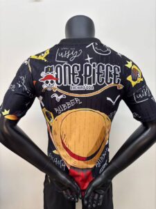 Back view of a mannequin wearing a black One Piece themed jacket with a large hamburger graphic across the back and logo text above it at the center.