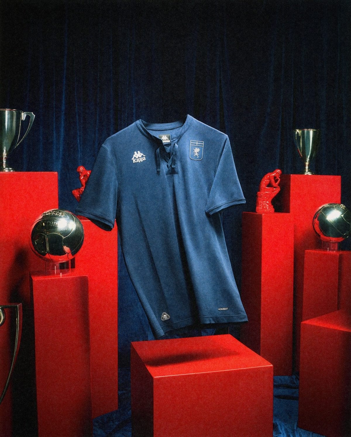 Blue sports jersey on a display stand surrounded by red pedestals and trophies against a dark backdrop.