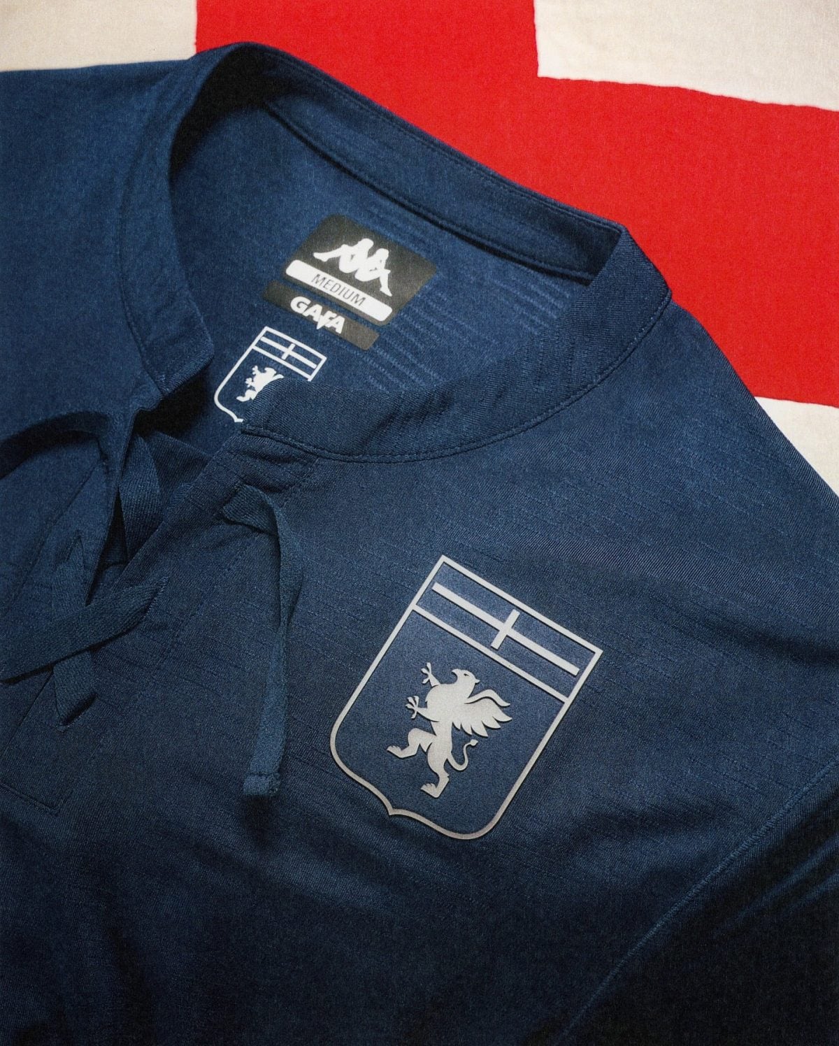 Navy polo shirt with a white lion crest inside a shield printed on the chest, GAP label and size tag reading 'Medium' visible inside the collar.