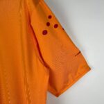 Close-up of orange fabric with red polka-dots along the sleeve seam without showing the full garment.