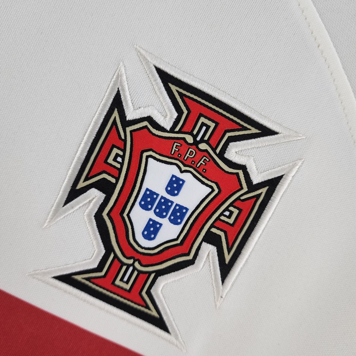 Close-up of a white fabric with a partially visible embroidered patch in red, black, and beige.